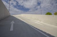 an empty roadway under a cloudy blue sky with a white arrow symbol on the left