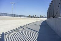 an empty roadway with black fenced off area and a blue sky in the background