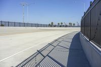 an empty roadway with black fenced off area and a blue sky in the background