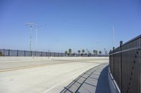 an empty roadway with black fenced off area and a blue sky in the background