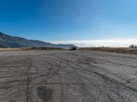 an empty asphalt roadway with mountains in the background and a blue sky in the foreground