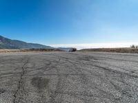 an empty asphalt roadway with mountains in the background and a blue sky in the foreground