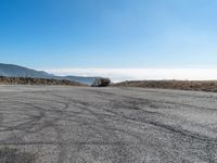 an empty asphalt roadway with mountains in the background and a blue sky in the foreground