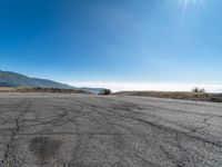 an empty asphalt roadway with mountains in the background and a blue sky in the foreground