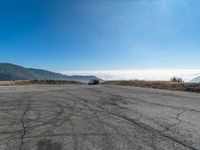 an empty asphalt roadway with mountains in the background and a blue sky in the foreground