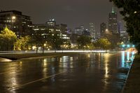 a view of an empty roadway at night in the city skyline with cars going by