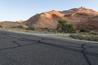 a empty roadway between some cliffs near by trees and bushes, with a yellow line