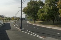 the empty roadway is empty at the end of the day with street lamps on the corner