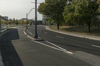 the empty roadway is empty at the end of the day with street lamps on the corner