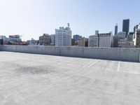 an empty parking lot on the rooftop of a building near a city skyline with skyscrapers