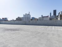 an empty parking lot on the rooftop of a building near a city skyline with skyscrapers
