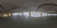 a wide angle view of an empty room with arches and columns with a person on a skateboard jumping in it