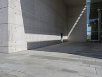 a empty room with a concrete wall and a red fire hydrant in it, as the sun shines on the stone floor