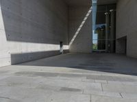 a empty room with a concrete wall and a red fire hydrant in it, as the sun shines on the stone floor