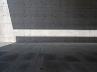 a empty room with a concrete wall and a red fire hydrant in it, as the sun shines on the stone floor