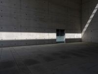 a empty room with a concrete wall and a red fire hydrant in it, as the sun shines on the stone floor
