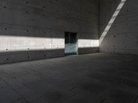 a empty room with a concrete wall and a red fire hydrant in it, as the sun shines on the stone floor