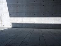 a empty room with a concrete wall and a red fire hydrant in it, as the sun shines on the stone floor