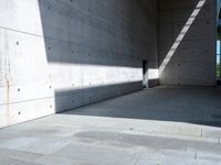 a empty room with a concrete wall and a red fire hydrant in it, as the sun shines on the stone floor