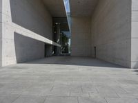 a empty room with a concrete wall and a red fire hydrant in it, as the sun shines on the stone floor