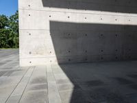 a empty room with a concrete wall and a red fire hydrant in it, as the sun shines on the stone floor