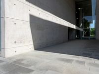 a empty room with a concrete wall and a red fire hydrant in it, as the sun shines on the stone floor