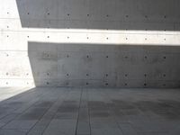 a empty room with a concrete wall and a red fire hydrant in it, as the sun shines on the stone floor