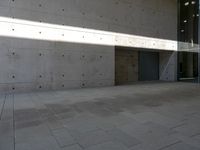 a empty room with a concrete wall and a red fire hydrant in it, as the sun shines on the stone floor