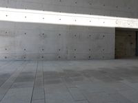 a empty room with a concrete wall and a red fire hydrant in it, as the sun shines on the stone floor