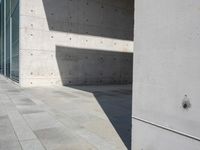 a empty room with a concrete wall and a red fire hydrant in it, as the sun shines on the stone floor