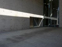 a empty room with a concrete wall and a red fire hydrant in it, as the sun shines on the stone floor