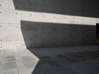 a empty room with a concrete wall and a red fire hydrant in it, as the sun shines on the stone floor