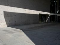 a empty room with a concrete wall and a red fire hydrant in it, as the sun shines on the stone floor