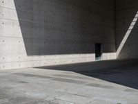 a empty room with a concrete wall and a red fire hydrant in it, as the sun shines on the stone floor