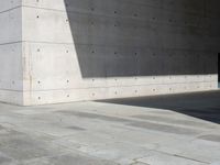 a empty room with a concrete wall and a red fire hydrant in it, as the sun shines on the stone floor