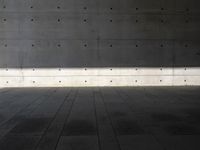 a empty room with a concrete wall and a red fire hydrant in it, as the sun shines on the stone floor