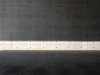 a empty room with a concrete wall and a red fire hydrant in it, as the sun shines on the stone floor