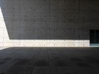 a empty room with a concrete wall and a red fire hydrant in it, as the sun shines on the stone floor