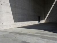 a empty room with a concrete wall and a red fire hydrant in it, as the sun shines on the stone floor