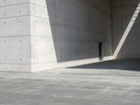 a empty room with a concrete wall and a red fire hydrant in it, as the sun shines on the stone floor