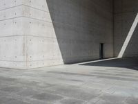 a empty room with a concrete wall and a red fire hydrant in it, as the sun shines on the stone floor
