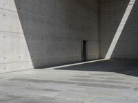 a empty room with a concrete wall and a red fire hydrant in it, as the sun shines on the stone floor