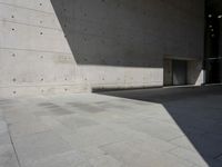 a empty room with a concrete wall and a red fire hydrant in it, as the sun shines on the stone floor