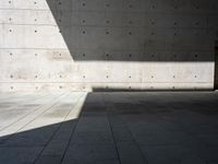 a empty room with a concrete wall and a red fire hydrant in it, as the sun shines on the stone floor