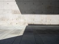 a empty room with a concrete wall and a red fire hydrant in it, as the sun shines on the stone floor