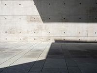 a empty room with a concrete wall and a red fire hydrant in it, as the sun shines on the stone floor