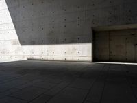 a empty room with a concrete wall and a red fire hydrant in it, as the sun shines on the stone floor