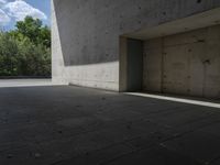 a empty room with a concrete wall and a red fire hydrant in it, as the sun shines on the stone floor