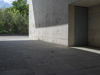 a empty room with a concrete wall and a red fire hydrant in it, as the sun shines on the stone floor