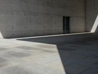 a empty room with a concrete wall and a red fire hydrant in it, as the sun shines on the stone floor